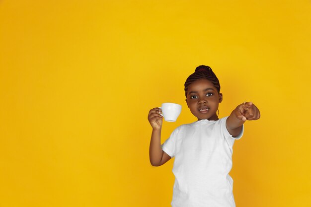 Portrait de petite fille afro-américaine isolé sur studio jaune