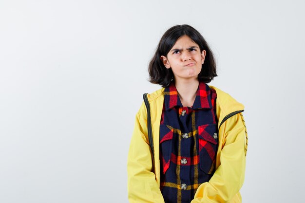 Portrait de petite fille courbant les lèvres en chemise à carreaux, veste et vue de face réfléchie