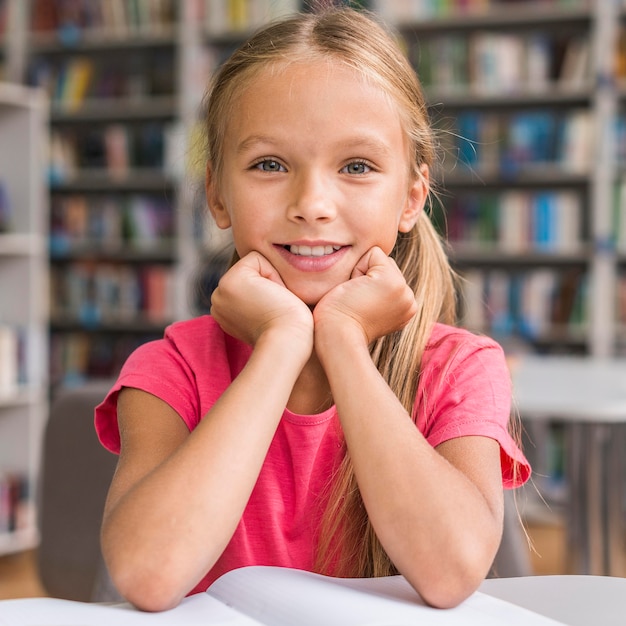 Portrait de petite fille à faire ses devoirs dans la bibliothèque