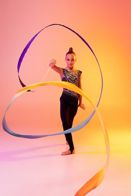 Portrait de petite fille, formation d'artiste de gymnastique rythmique isolée sur couleur