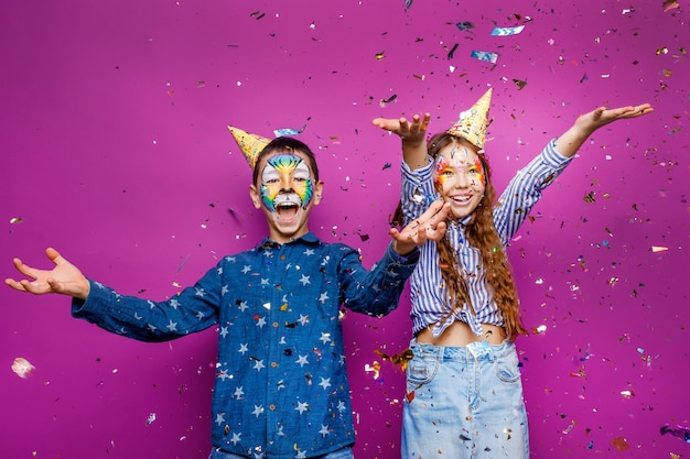 Photo gratuite portrait d'une petite fille et d'un garçon joyeux et positifs, amusez-vous isolé sur un mur de couleur violette en serpentine volant