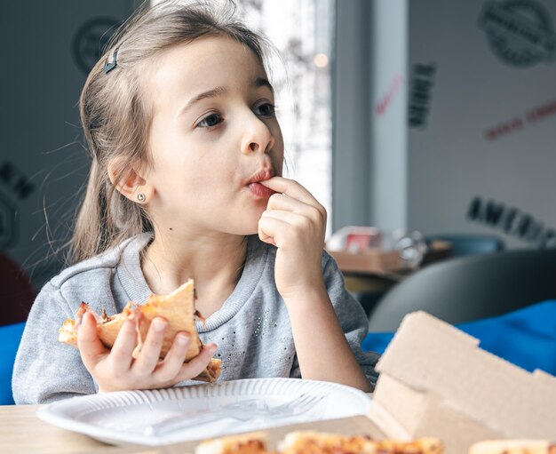 Portrait d'une petite fille avec un morceau de pizza appétissant