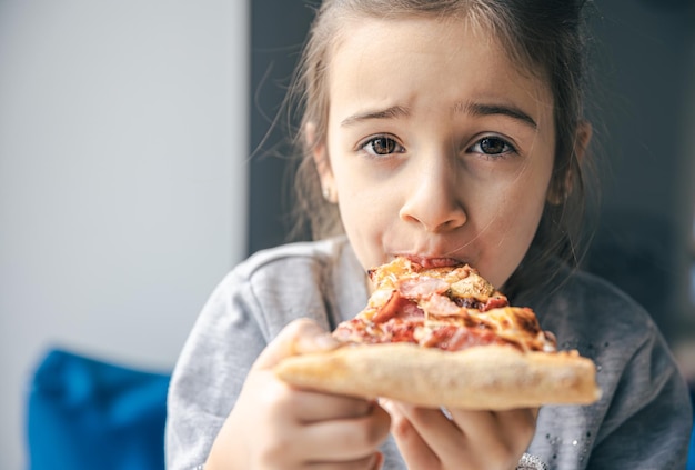 Portrait d'une petite fille avec un morceau de pizza appétissant