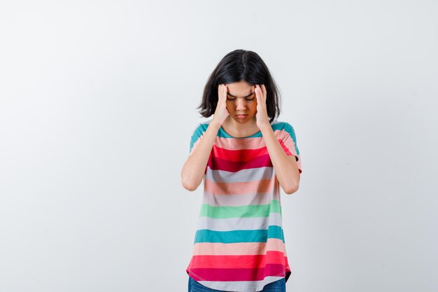 Portrait de petite fille souffrant de forts maux de tête en t-shirt et à la vue de face fatiguée