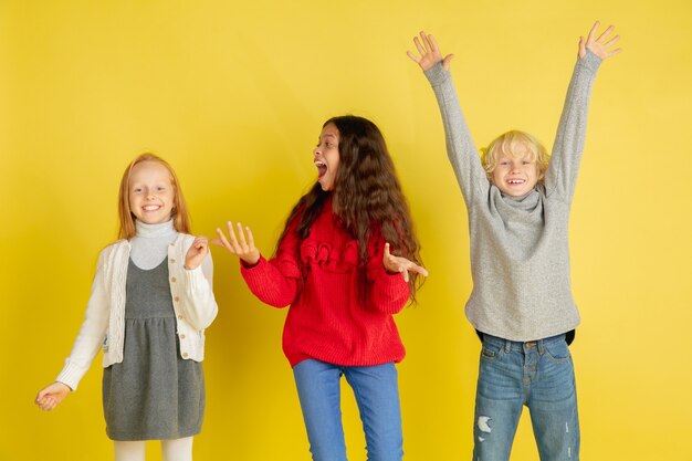 Portrait de petits enfants caucasiens avec des émotions vives isolés sur un studio jaune