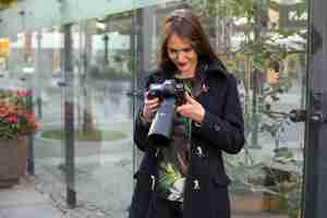 Photo gratuite portrait d'une photographe professionnelle dans la rue en train de photographier sur un appareil photo. séance photo séance photo en ville