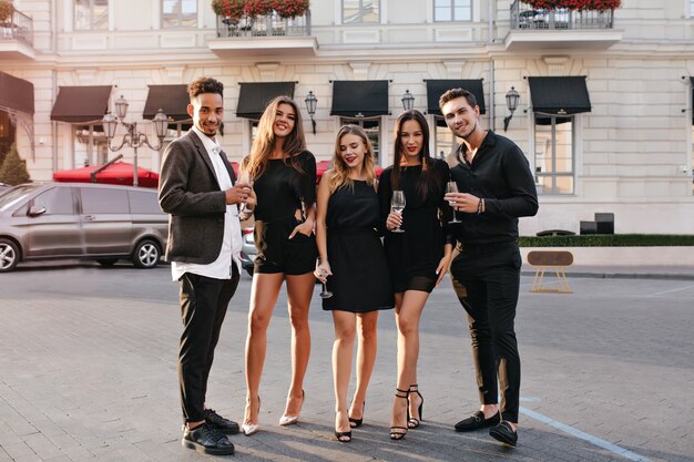 Portrait en pied du modèle féminin à la mode dans une pose confiante debout entre amis