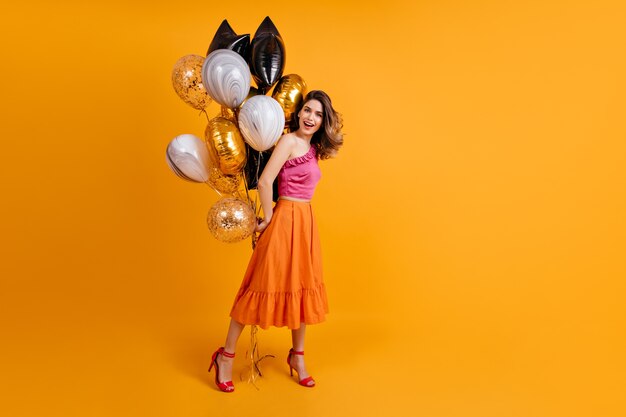 Portrait en pied de femme brune posant à la fête