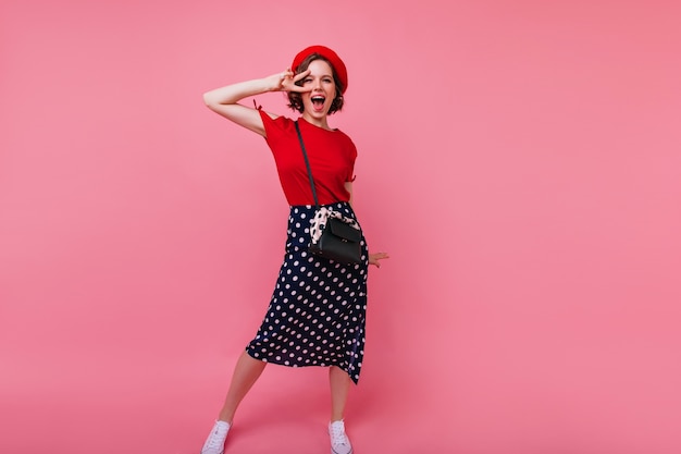 Portrait en pied d'une femme française excitée s'amusant. Dame caucasienne Jocund en danse de béret rouge.