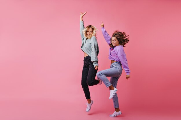 Portrait en pied de filles blanches sautant exprimant des émotions heureuses. Portrait des meilleurs amis drôles de danse ensemble.
