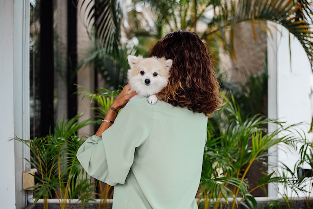 Portrait en plein air de femme bronzée européenne bouclés détient happy pet dog pomeranian spitz