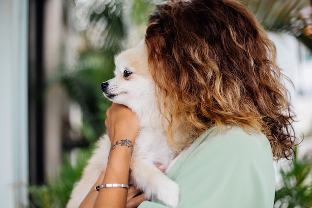 Portrait en plein air de femme bronzée européenne bouclés détient happy pet dog pomeranian spitz