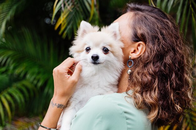 Portrait en plein air de femme bronzée européenne bouclés détient happy pet dog pomeranian spitz