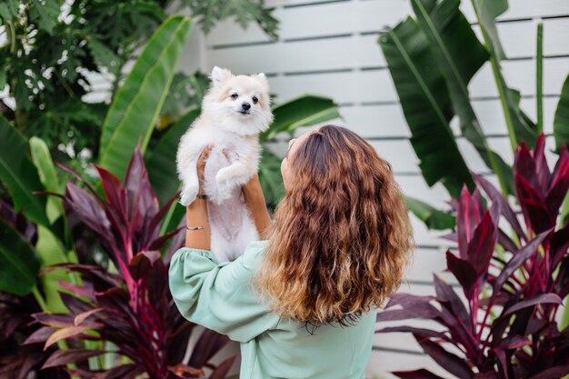 Portrait en plein air de femme bronzée européenne bouclés détient happy pet dog pomeranian spitz