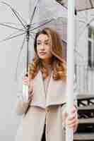 Photo gratuite portrait de pluie de belle jeune femme avec parapluie