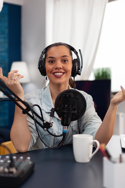 Portrait d'un présentateur souriant diffusant un podcast à l'aide d'un microphone. Influenceur des médias sociaux avec un casque enregistrant un flux en direct sur une caméra. Créateur de contenu diffusant en direct en home studio.