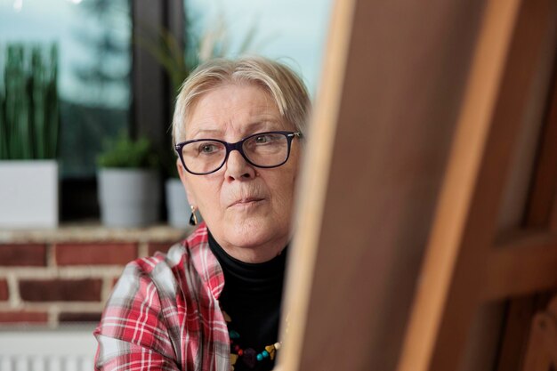 Portrait d'un professeur de peintre aîné dessinant un croquis sur une toile graphique pendant des cours d'art dans un lieu de travail de mur de briques. Groupe de personnes apprenant à dessiner en utilisant la technique d'illustration. Les résolutions du nouvel an