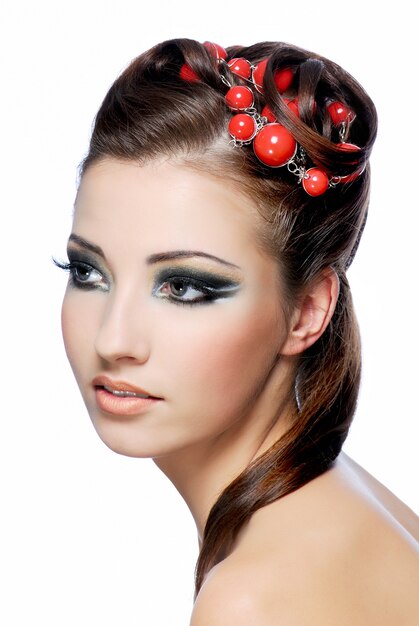 Portrait de profil d'une jolie jeune femme avec une coiffure de créativité et un maquillage élégant