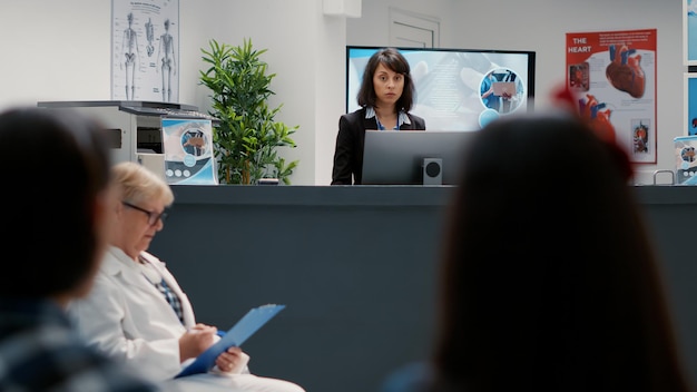 Photo gratuite portrait d'une réceptionniste hospitalière travaillant au comptoir administratif pour aider les patients à prendre rendez-vous. secrétaire féminine apportant son soutien aux soins de santé à la réception.