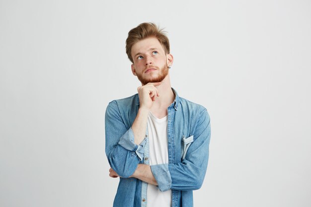 Portrait de rêveur jeune beau mec pensant rêver avec la main sur le menton.