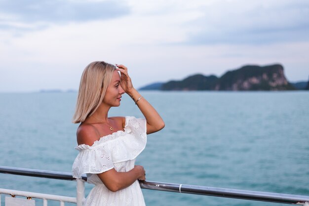 Portrait romantique de femme en robe blanche naviguant sur un grand ferry