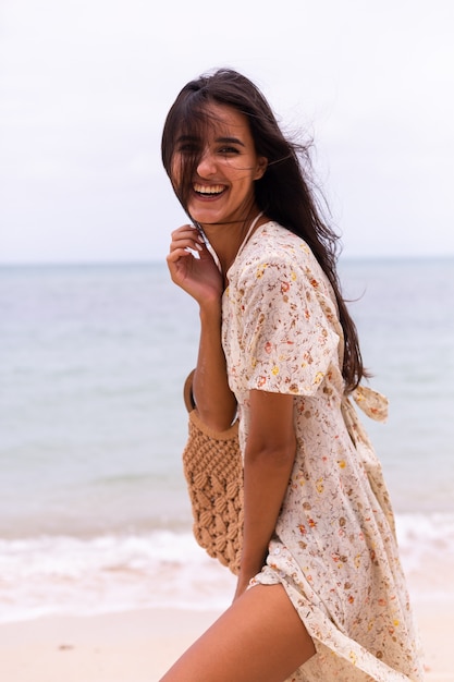 Portrait romantique de femme en robe longue sur la plage au jour nuageux venteux.