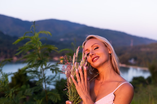 Portrait romantique de jeune femme caucasienne en robe d'été profitant de la détente dans le parc sur la montagne avec une vue imprenable sur la mer tropicale