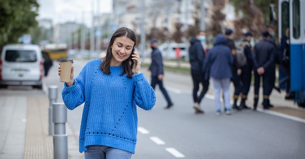 Portrait de rue d'une jeune femme parlant au téléphone dans la ville près de la chaussée