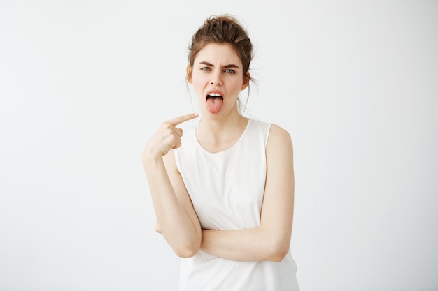 Photo gratuite portrait de s'ennuyer mécontent jeune femme pointant le doigt sur sa langue.