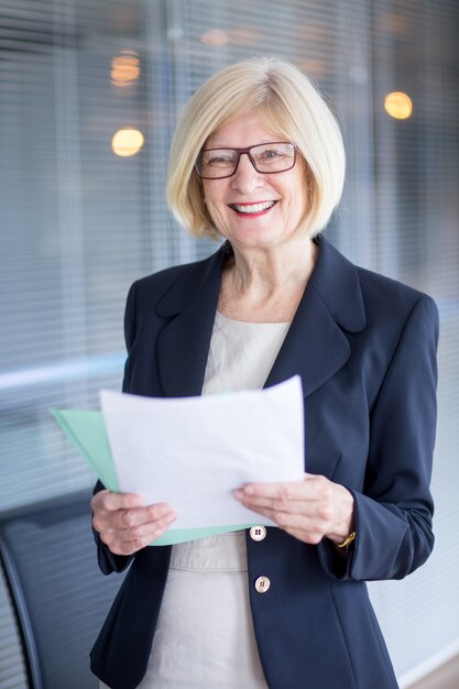 Portrait de secrétaire senior souriant avec des papiers