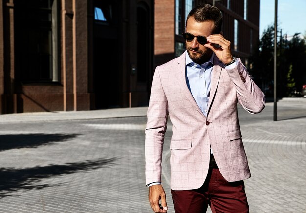 Portrait de sexy beau mannequin homme d'affaires habillé en costume élégant posant sur fond de rue. Métrosexuel