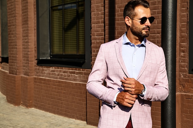 Photo gratuite portrait de sexy beau mannequin homme d'affaires habillé en costume élégant posant près du mur de briques sur le fond de la rue. métrosexuel