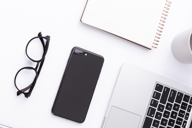 Portrait d'un smartphone, d'un ordinateur portable, de lunettes et d'un ordinateur portable sur une surface blanche