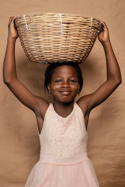 Photo gratuite portrait smiley girl avec panier de paille sur la tête