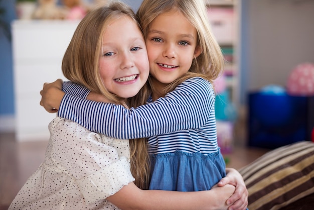 Photo gratuite portrait de sœurs embrassant dans le salon