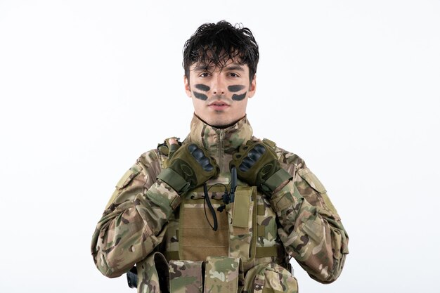 Portrait de soldat masculin en tenue de camouflage prêt pour la guerre sur un mur blanc