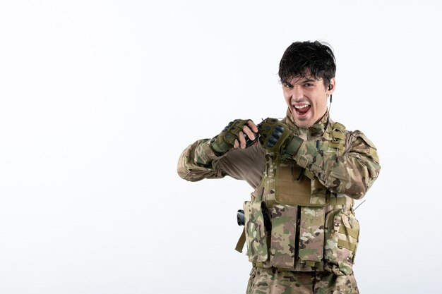 Portrait de soldat masculin en uniforme militaire avec grenade sur mur blanc