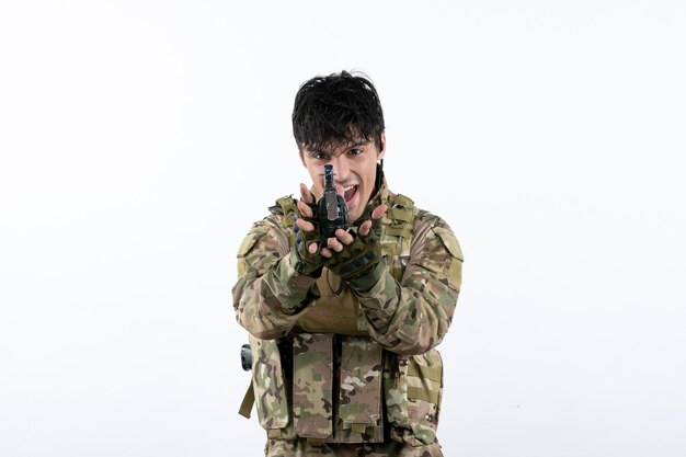 Portrait de soldat masculin en uniforme militaire avec grenade sur mur blanc
