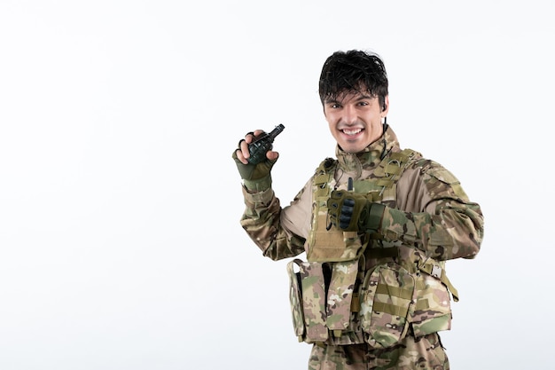 Portrait de soldat masculin en uniforme militaire avec grenade sur mur blanc