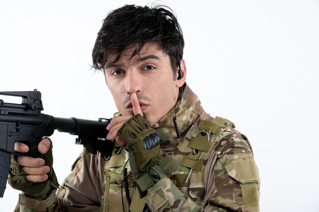 Portrait de soldat masculin en uniforme militaire avec mur blanc de mitrailleuse