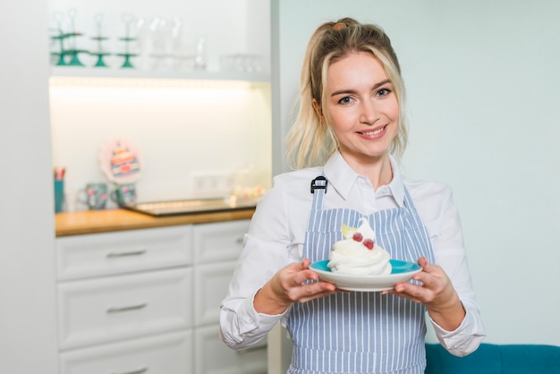 Photo gratuite portrait souriant d'un entrepreneur femme tenant la meringue sur une assiette