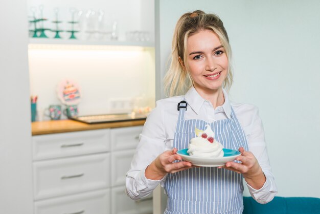 Portrait souriant d&#39;un entrepreneur femme tenant la meringue sur une assiette