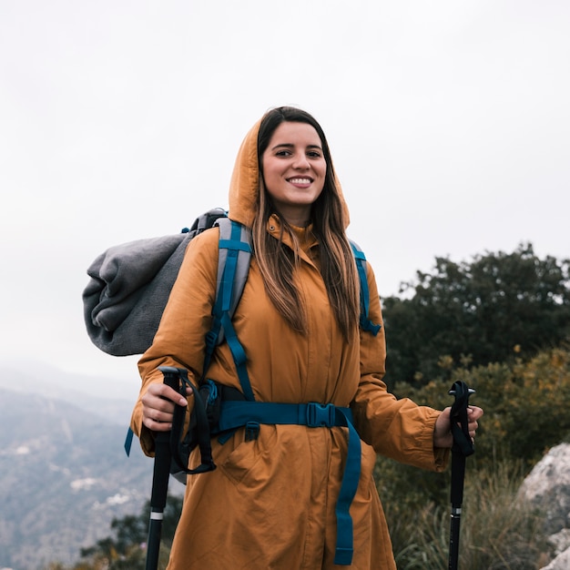 Portrait, de, a, souriant, femme, randonneur, tenue, bâton randonnée, regarder appareil-photo