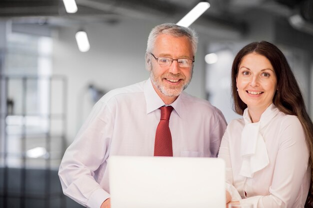 Portrait de souriant homme d&#39;affaires senior et femme d&#39;affaires avec ordinateur portable au bureau