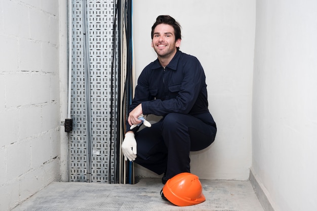 Photo gratuite portrait de souriant jeune électricien au lieu de travail