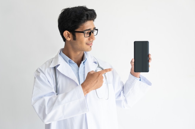 Portrait de souriant jeune médecin à lunettes montrant le téléphone mobile.