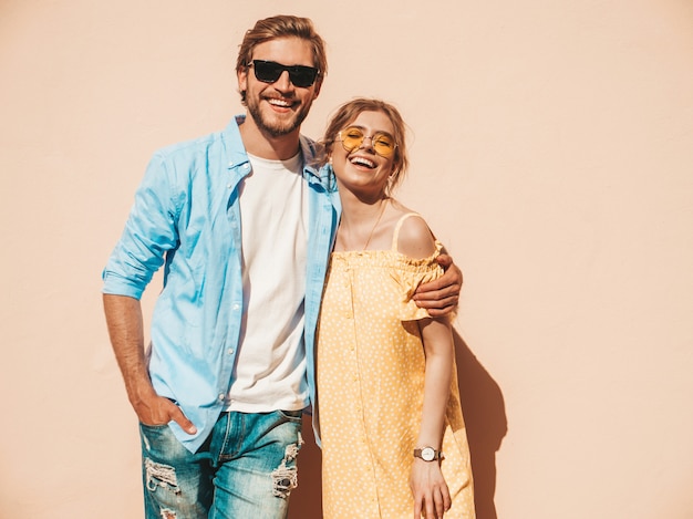 Portrait de souriante belle fille et son beau petit ami. Femme en robe d'été décontractée et homme en jeans. Famille joyeuse heureuse. Femme s'amusant dans la rue près du mur