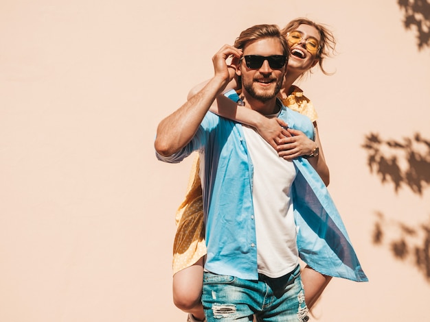 Photo gratuite portrait de souriante belle fille et son beau petit ami. femme en robe d'été décontractée et homme en jeans. famille joyeuse heureuse. femme s'amusant dans la rue près du mur