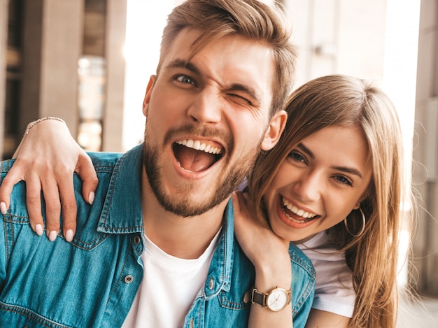 Portrait de souriante belle fille et son beau petit ami. Femme en vêtements de jeans d'été décontracté. . Un clin d'oeil