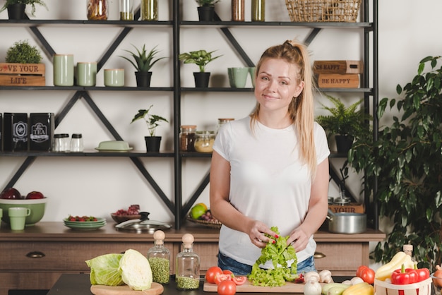 Portrait de souriante blonde jeune femme préparant la nourriture